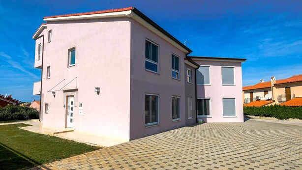 Un bâtiment moderne à deux étages, doté d’un toit plat, d’une allée pavée et d’une pelouse bien entretenue.