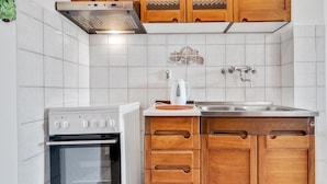 A kitchen with white tiles, wooden cabinets, a stove, and a sink.