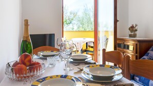 A dining table set with plates, glasses, a bottle, and fruit.