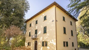 Edifici de dues plantes amb façana simètrica, nombroses finestres amb persianes i entrada central amb arcada.