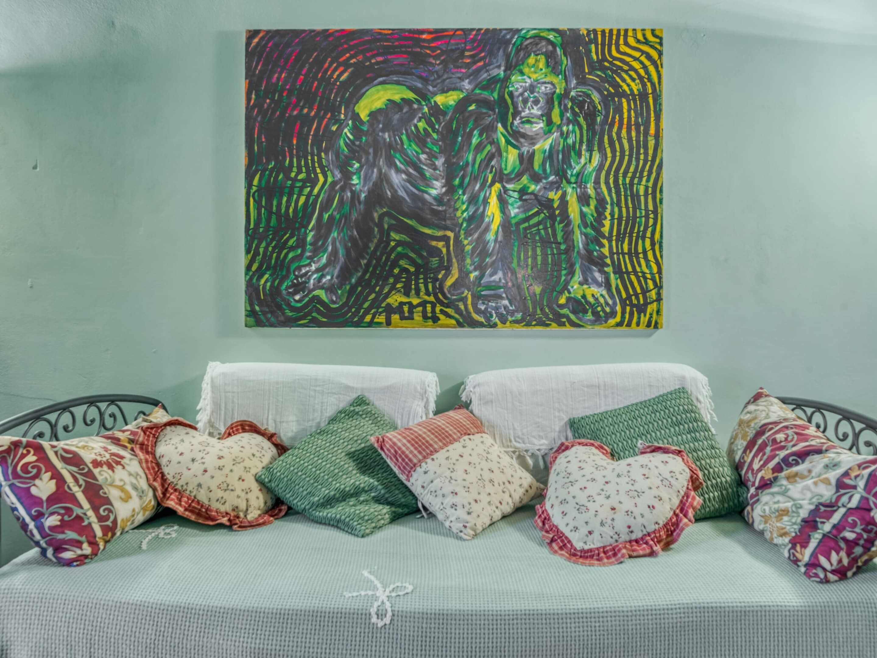 A bed with a green sheet and decorative pillows in various patterns.