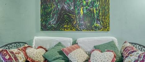 A bed with a green sheet and decorative pillows in various patterns.