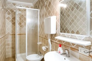 Une salle de bain équipée d’une douche, de toilettes, d’un lavabo et d’un miroir.