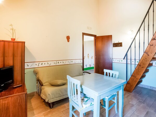 Un salon confortable avec un canapé, une table à manger et un téléviseur posé sur un meuble en bois.