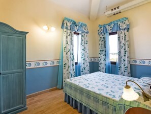 Une chambre à coucher avec un lit, des rideaux, une armoire et un luminaire fixé au mur.