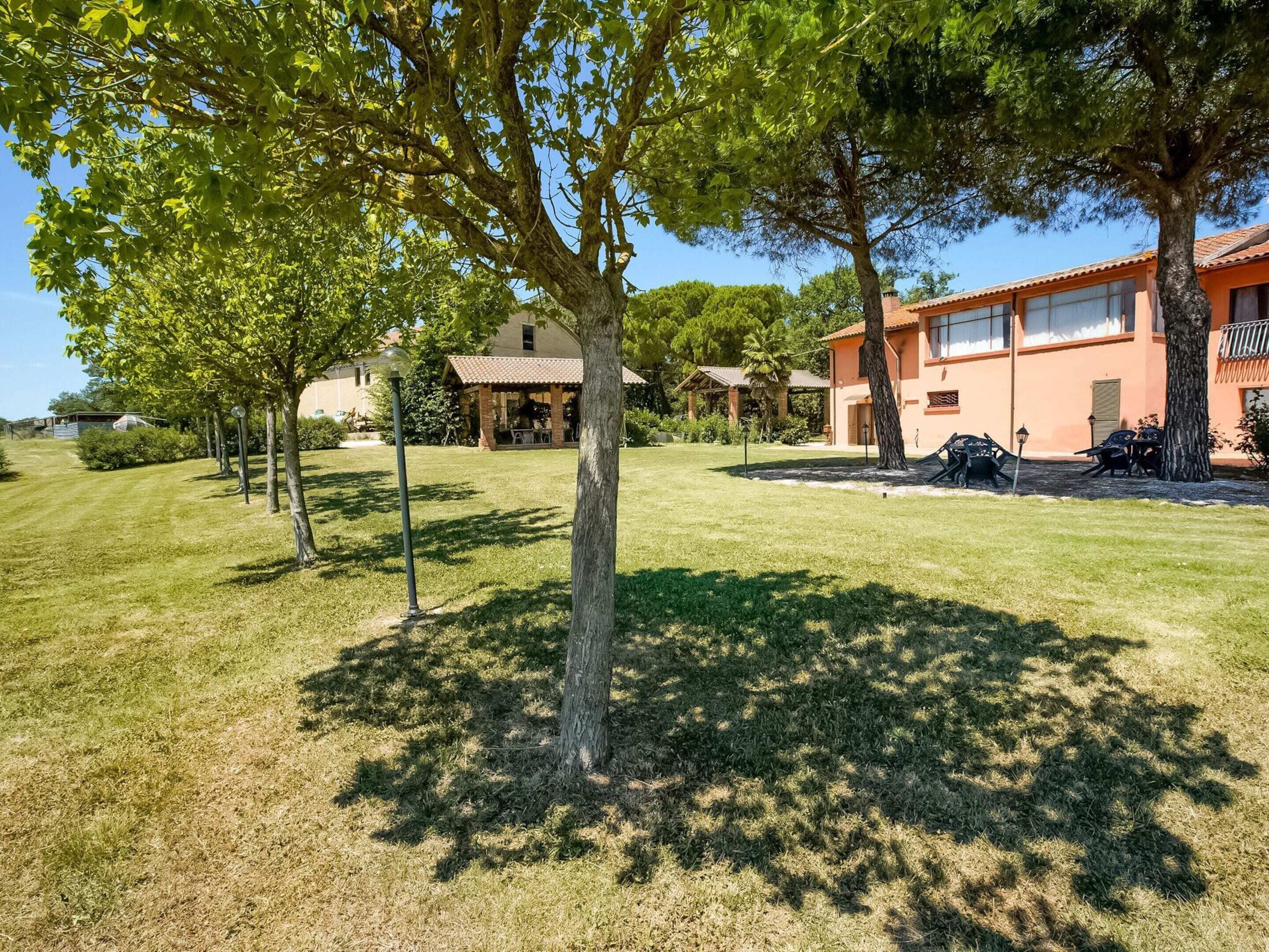 A residential property with a well-maintained lawn, multiple trees, and a two-story house with a tiled roof.