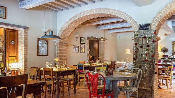 Un restaurant avec des arches en briques, des tables et des chaises en bois.