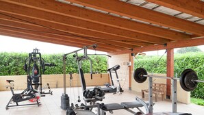 A covered outdoor gym area with exercise equipment including a treadmill, weight bench, and various free weights. - Holiday Home in Magione Near Lake Trasimeno (Magione)