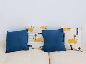 Ein Bett mit zwei Kissen, eines blau und eines weiß mit gelben Ankern.