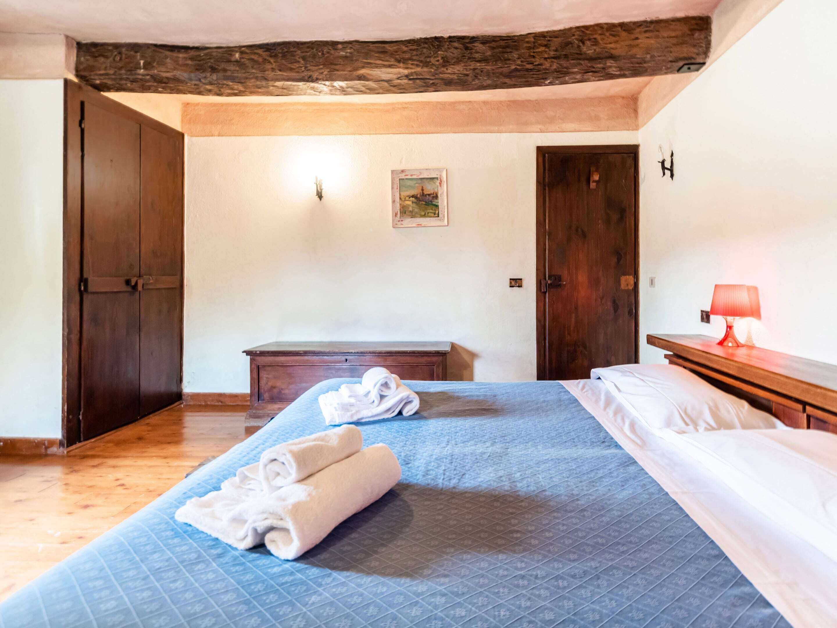 Une chambre à coucher avec un grand lit, un banc en bois et une table de chevet avec une lampe.