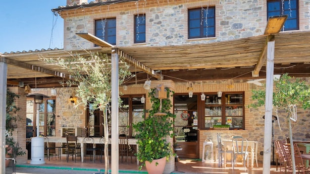 A stone building with a covered patio area, outdoor seating, and potted plants. - Cottage in Umbria With Pool & Garden (Citta della Pieve)