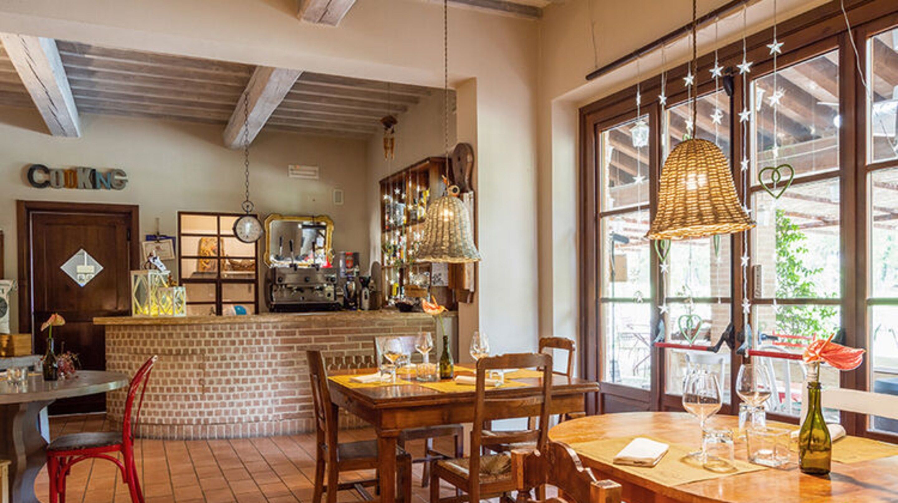 A cozy restaurant with wooden furniture, a brick counter, and large windows.