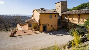 Un edificio a due piani con un cortile interno, un piccolo giardino e vista sul paesaggio circostante.