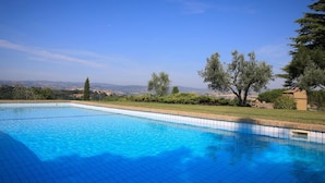 Una piscina rettangolare con acqua cristallina, circondata da un solarium piastrellato e un basso muretto in pietra.