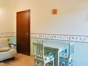 A room with a wooden door, a sofa, and a table with chairs. - Apartment in Castiglione Near Lake Trasimeno (Castiglione del Lago)
