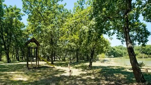 A park with a wooden play structure, a yellow slide, and a pond. - Holiday Home Near Castiglione del Lago (Castiglione del Lago)