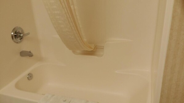 Una bañera con cortina de ducha, grifo y desagüe.