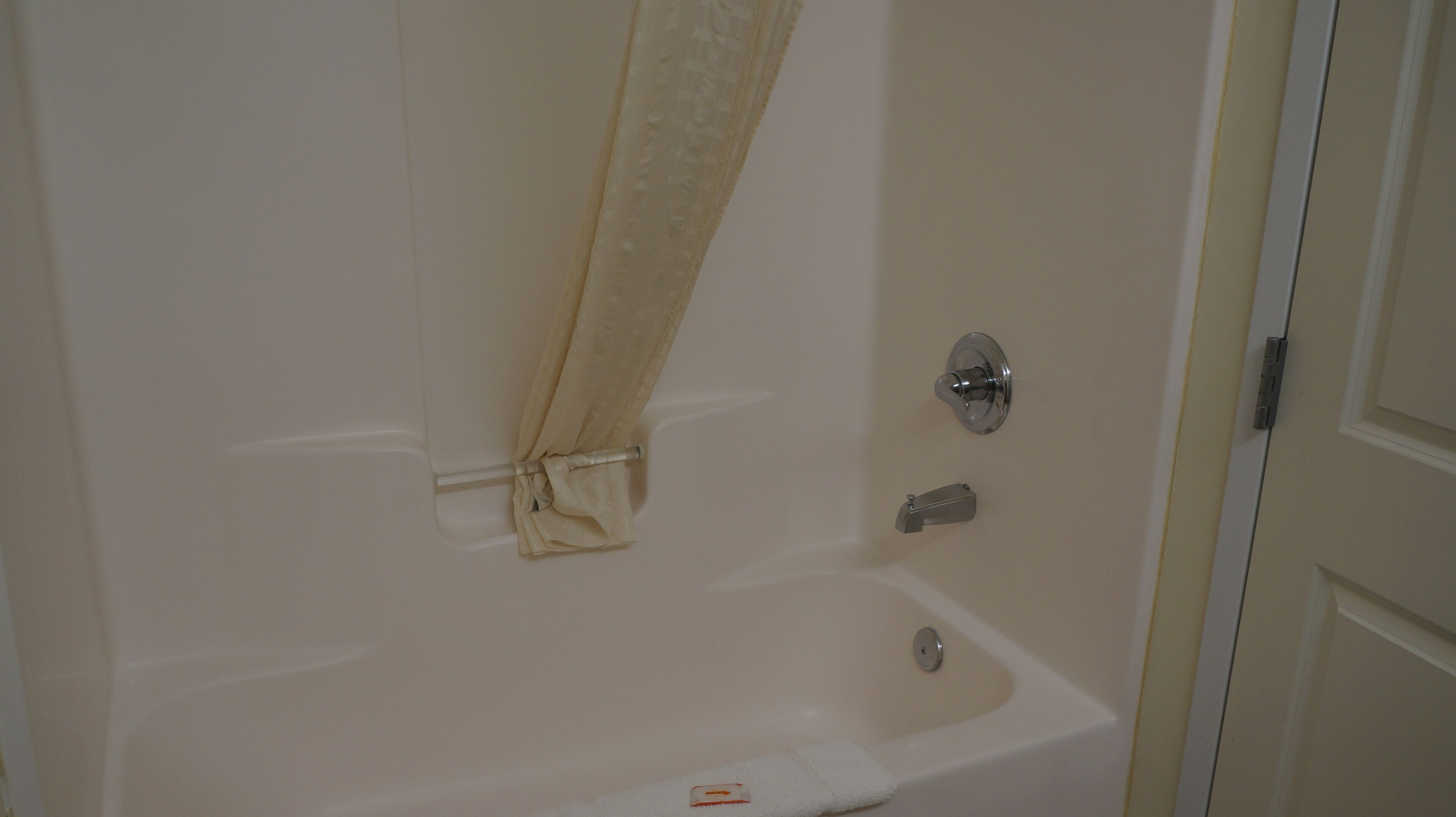 A bathroom with a bathtub, a shower curtain, and a door.