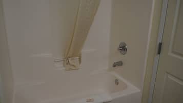 A bathroom with a bathtub, a shower curtain, and a door.
