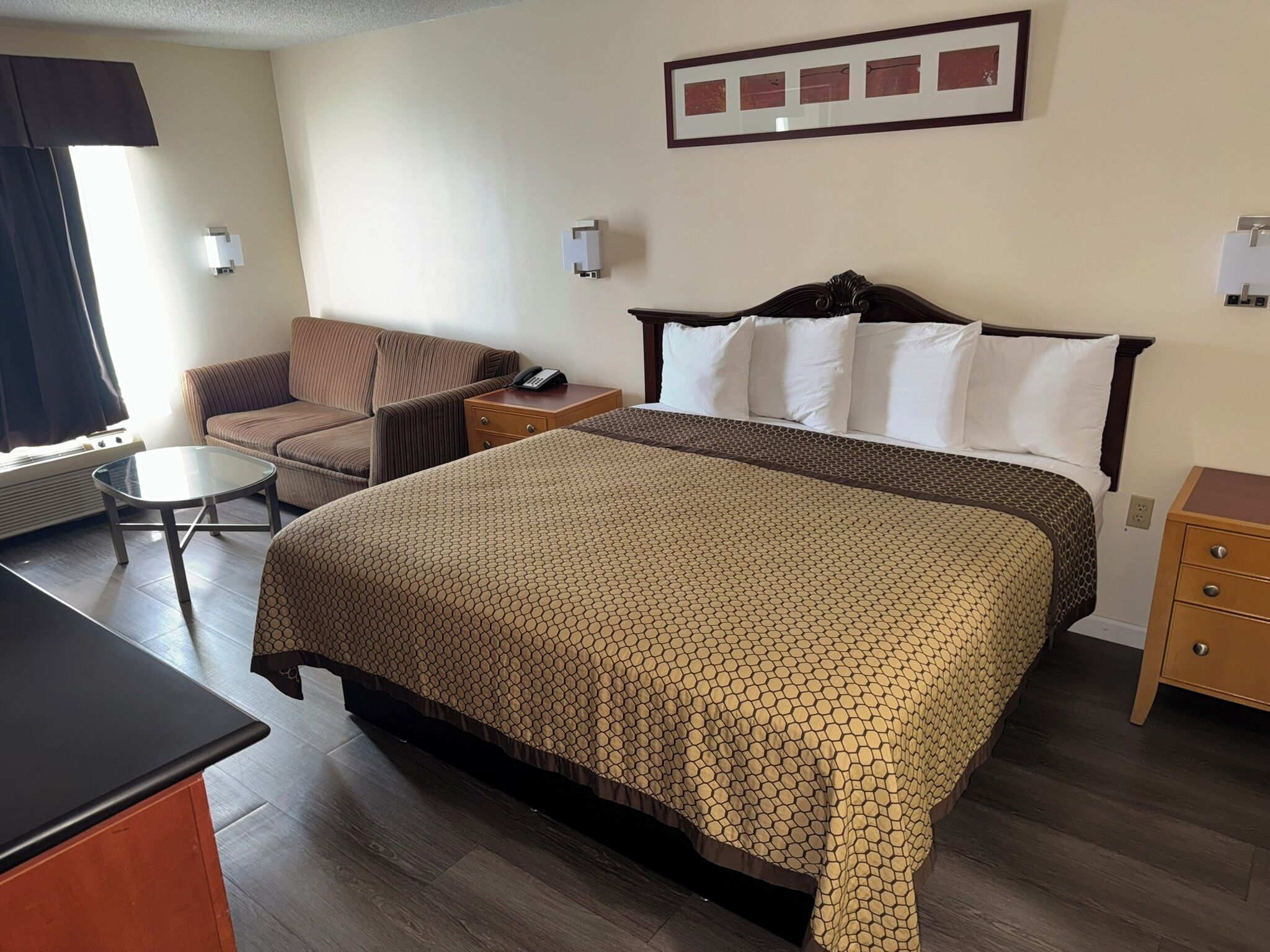 Una habitación de hotel con cama, una silla, una mesita y un escritorio.