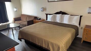 Una habitación de hotel con cama, una silla, una mesita y un escritorio.