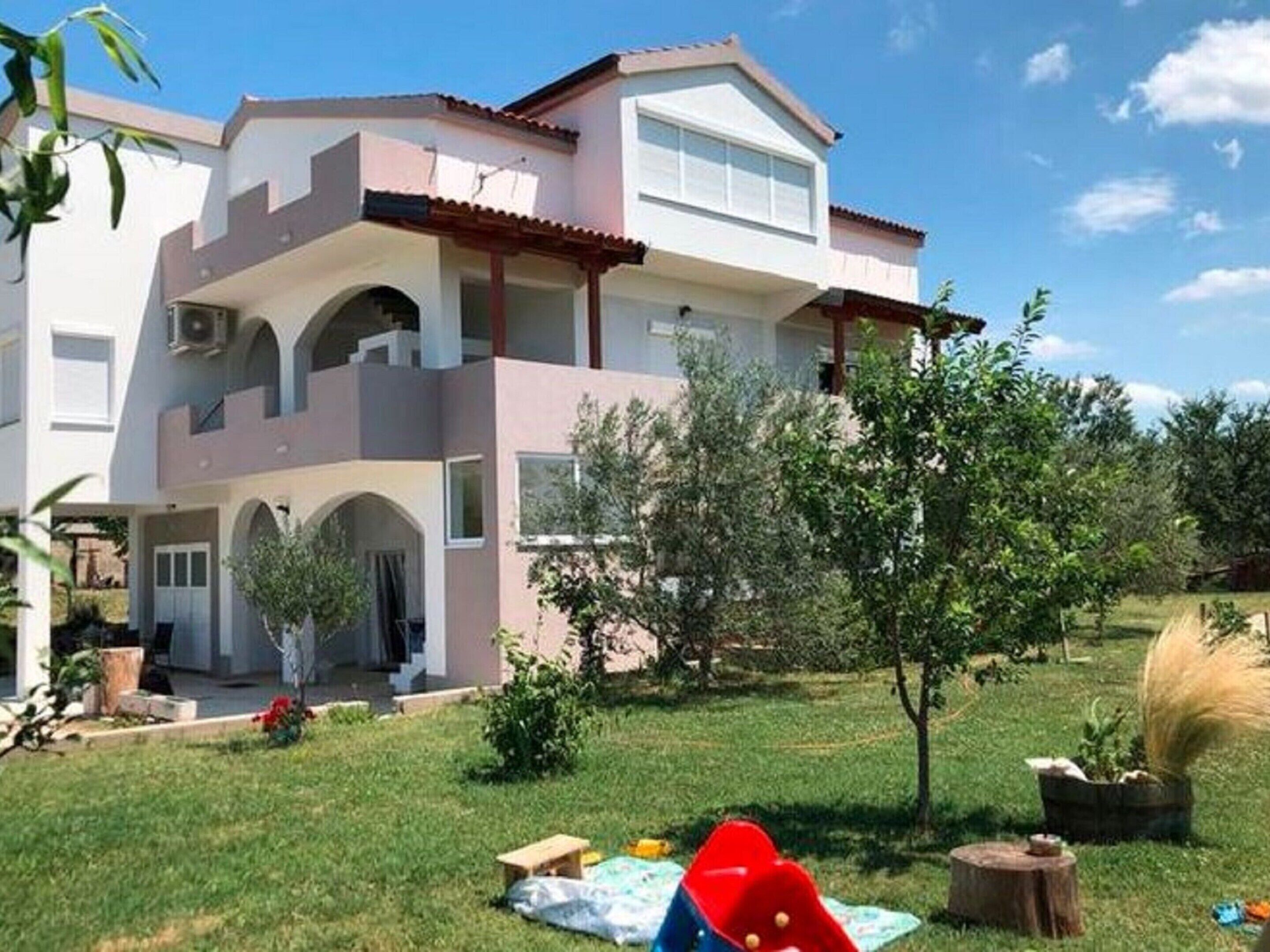 A two-story house with a covered patio and a grassy yard.