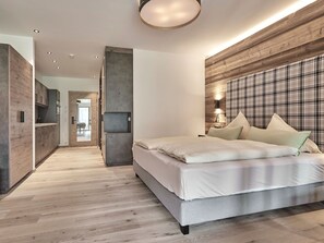 Un dormitorio moderno con una cama grande, un muro decorativo de madera y vistas a la cocina.