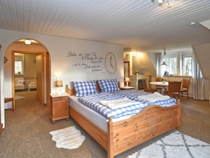 A cozy bedroom with a wooden bed, a wall clock, and a cozy fireplace. - Apartment Weissenbrunn Near Coburg (Weissenbrunn)