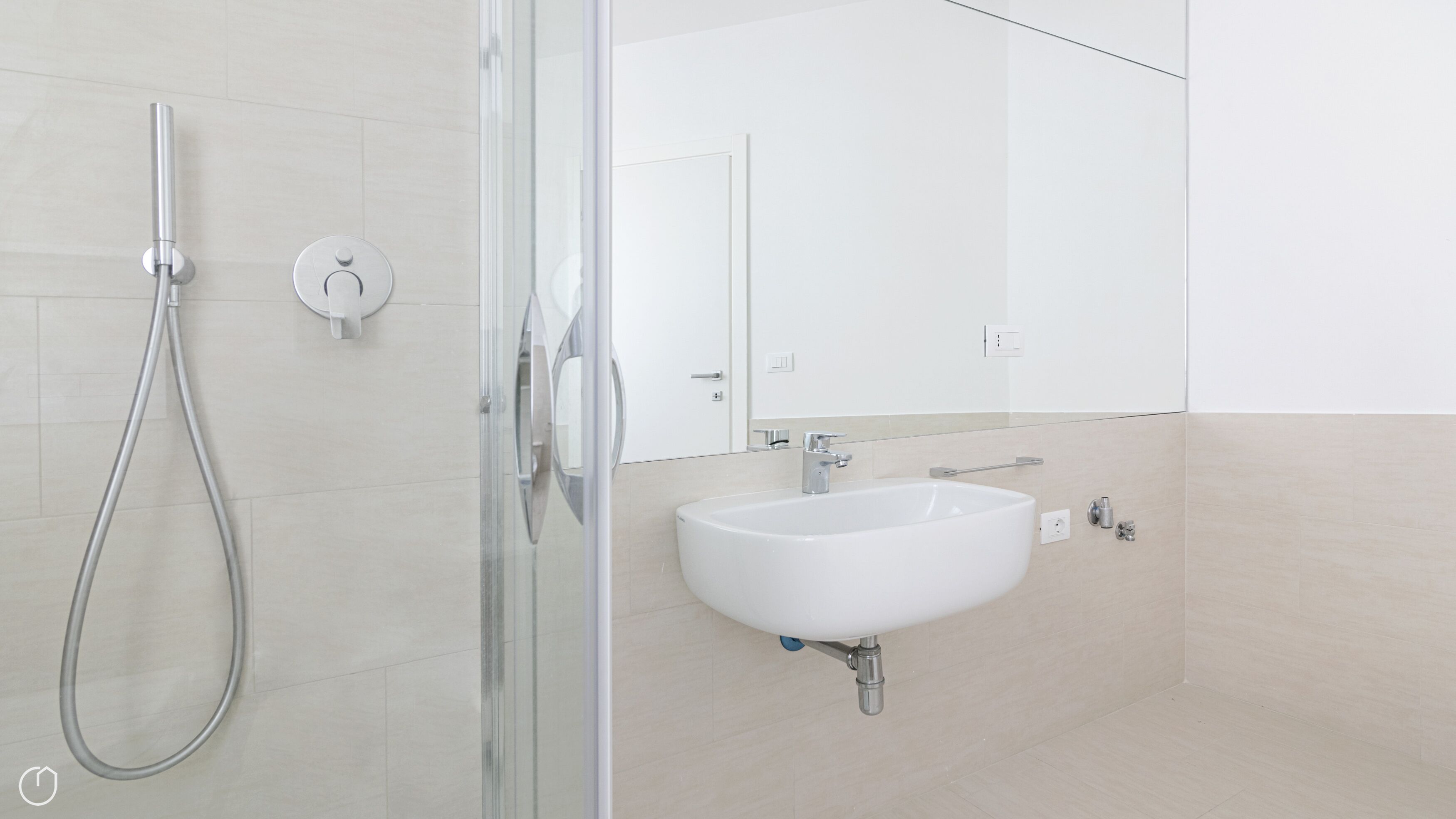 A modern bathroom with a glass-enclosed shower, a white sink, and a mirror.