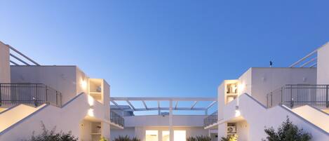 A modern building with a central courtyard, multiple balconies, and potted plants.