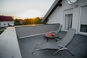 A rooftop terrace with two lounge chairs and a small table, featuring a sunset view. - Holiday Home Near Plitvice Lakes (Lovinac)