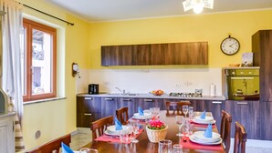 A dining area with a wooden table set for six, equipped with plates, glasses, and cutlery.