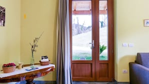 A room with a wooden door, a table with a basket of flowers, a vase, and a bottle.