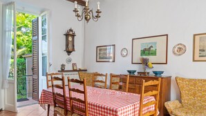 A dining area with a checkered tablecloth, wooden chairs, a clock, and framed pictures on the wall. - Belvilla by OYO Belle Epoque (Meina)