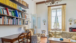 A cozy living room with a sofa, chairs, a wooden table, and a bookshelf filled with books. - Belvilla by OYO Belle Epoque (Meina)