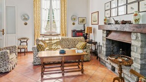 A cozy living room with a fireplace, floral-patterned furniture, and a bookshelf. - Belvilla by OYO Belle Epoque (Meina)