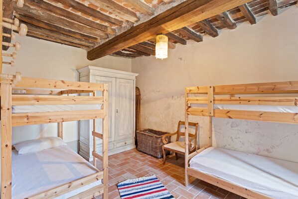 Una habitación con dos literas, una cesta de mimbre, una silla y un armario.
