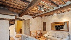 Une pièce au style rustique, avec des poutres apparentes, un grand canapé confortable, une table basse en bois et un miroir au mur.