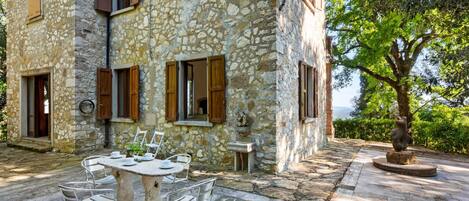 A stone building with a stone patio, outdoor seating, and a view of the landscape.