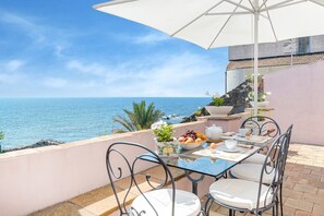A table set with a fruit bowl, teapot, and cups, overlooking a coastal view. - Holiday Home in Santa Tecla Near Etna Beach (Acireale)