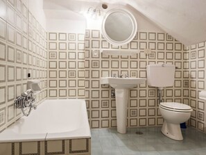 Een badkamer met een badkuip, wastafel, toilet en een spiegel.