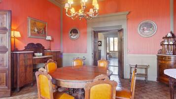 Une salle à manger avec une table et des chaises en bois, un lustre et des murs rouges.