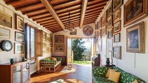 Un salon chaleureux avec un plafond en bois, un canapé vert à motifs floraux, un banc en bois et une petite table ronde.