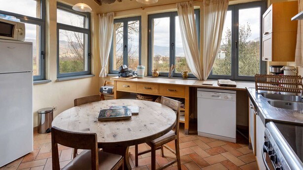 Une cuisine avec une table en bois, des chaises, un réfrigérateur, un lave-vaisselle et un évier.
