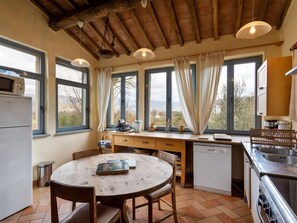 A kitchen with a wooden table, chairs, a refrigerator, a dishwasher, and a sink. - Tuscan Villa in Castiglion Fiorentino w/ Pool (Castiglion Fiorentino)