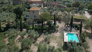 Une villa située dans un cadre rural, dotée d’une piscine et entourée d’oliviers et de collines.