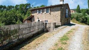 A stone house with a wooden fence, a gravel driveway, and a rural setting.