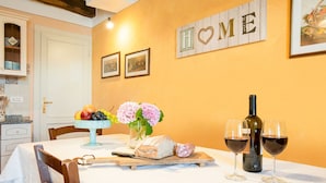 A dining table with a loaf of bread, a bottle of wine, and two glasses of wine.