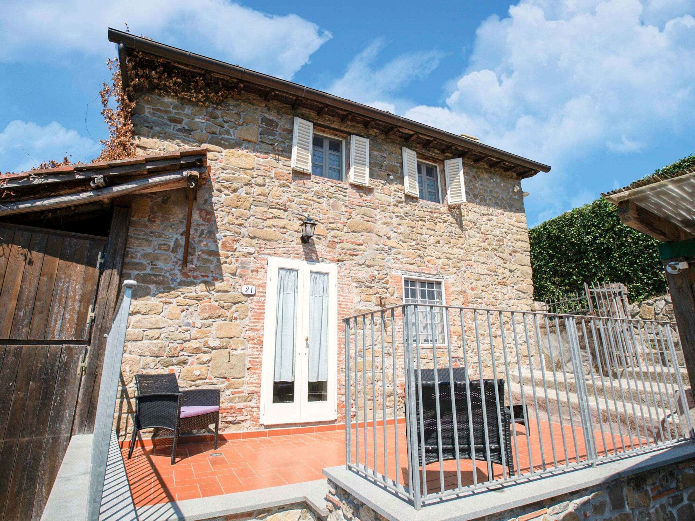Un edificio de piedra con un patio empedrado, una verja de metal y un letrero con el número 21.