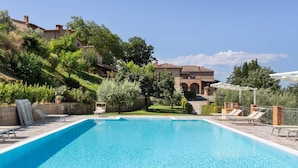 A swimming pool with lounge chairs, a stone building in the background, and a clear sky. - Holiday Home in Volterra With Pool & Views (Volterra)